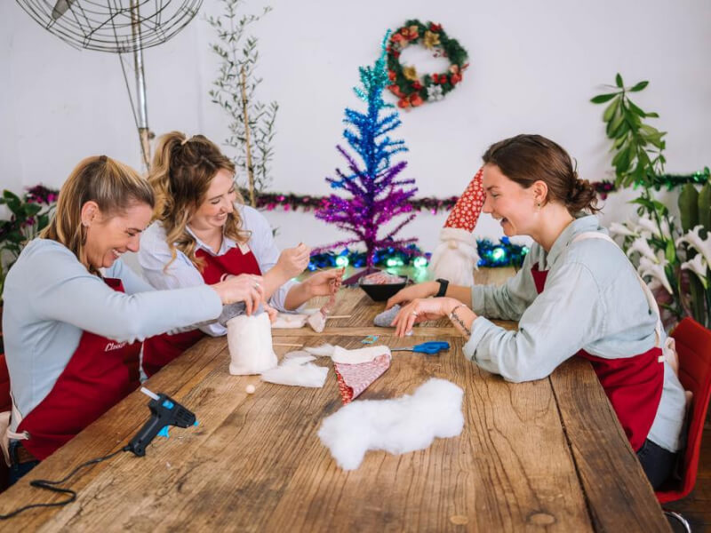 three women sitting around a wooden table at a sewing class